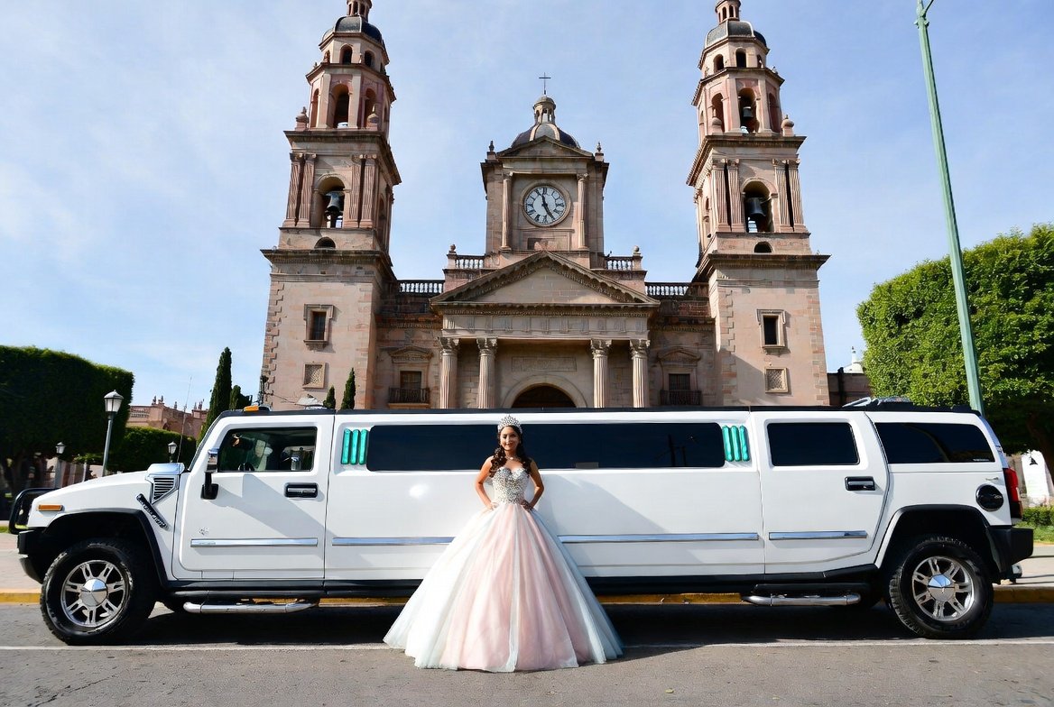 quinceañera tomandose una foto con su servicio de limusina en las afueras de una iglesia